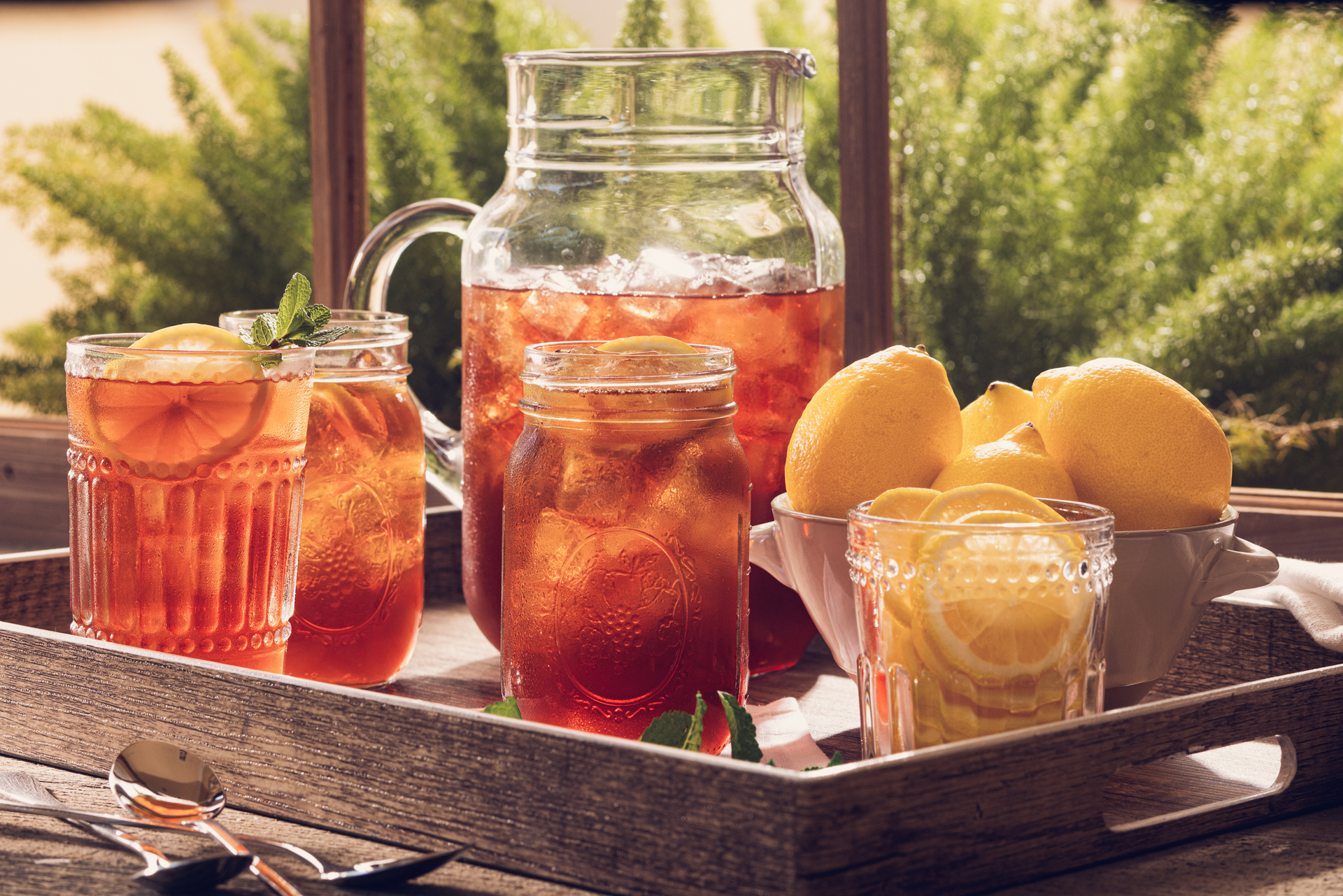 pitcher of iced tea and glasses on a tray on porch