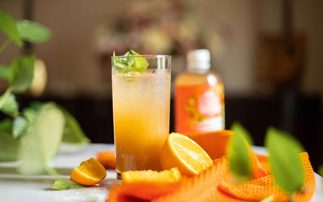 A brightly colored glass of Bubbly Satsuma Tea
