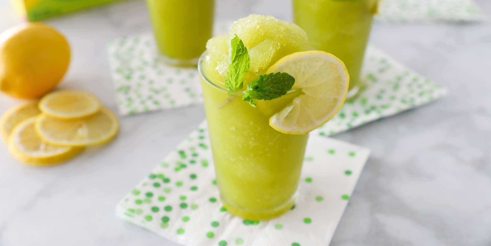 2 glasses of frozen Lemonita with mint, garnished with lemon and fresh mint, made with Luzianne Iced Green Tea