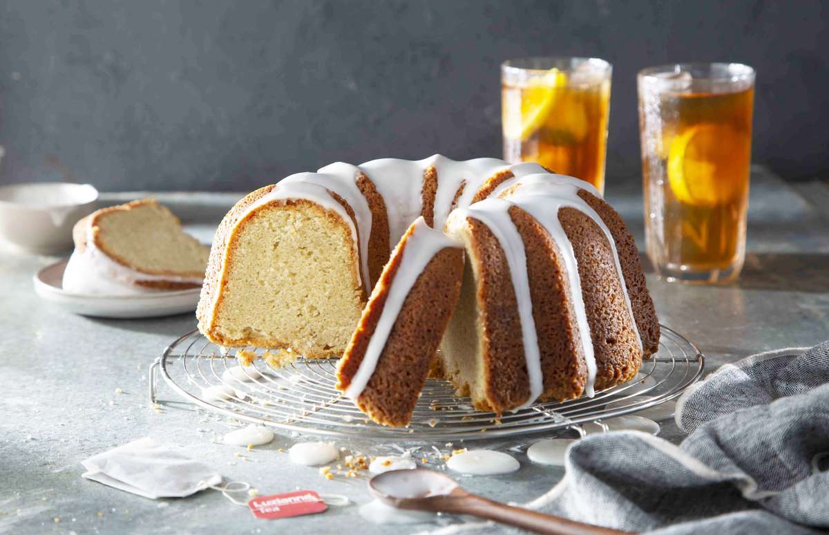 Sweet Tea Lemon Pound Cake on a cake plate, with tall glasses of Luzianne Iced Tea with lemon wedges in background.