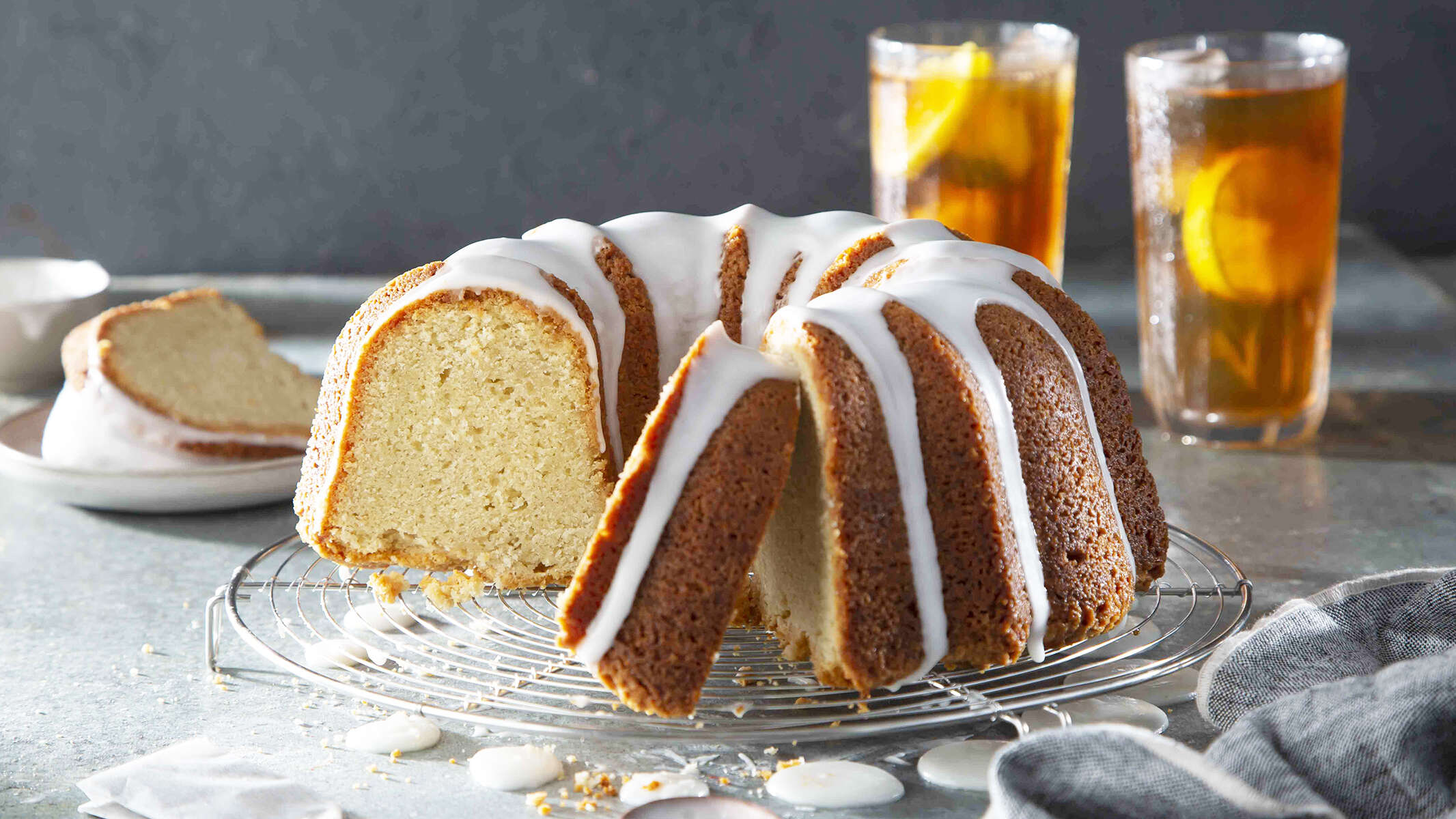 Sweet Tea Lemon Pound Cake on a cake plate, with tall glasses of Luzianne Iced Tea with lemon wedges in background.