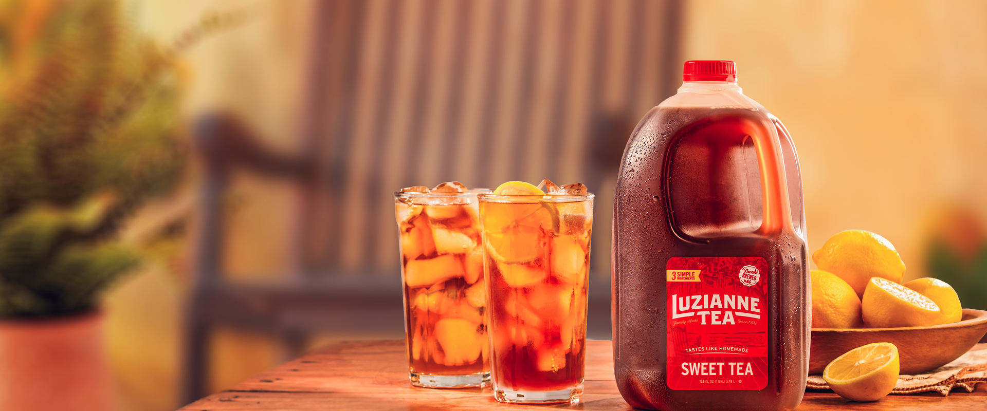Luzianne Tea gallon jug on a counter with glasses and lemons