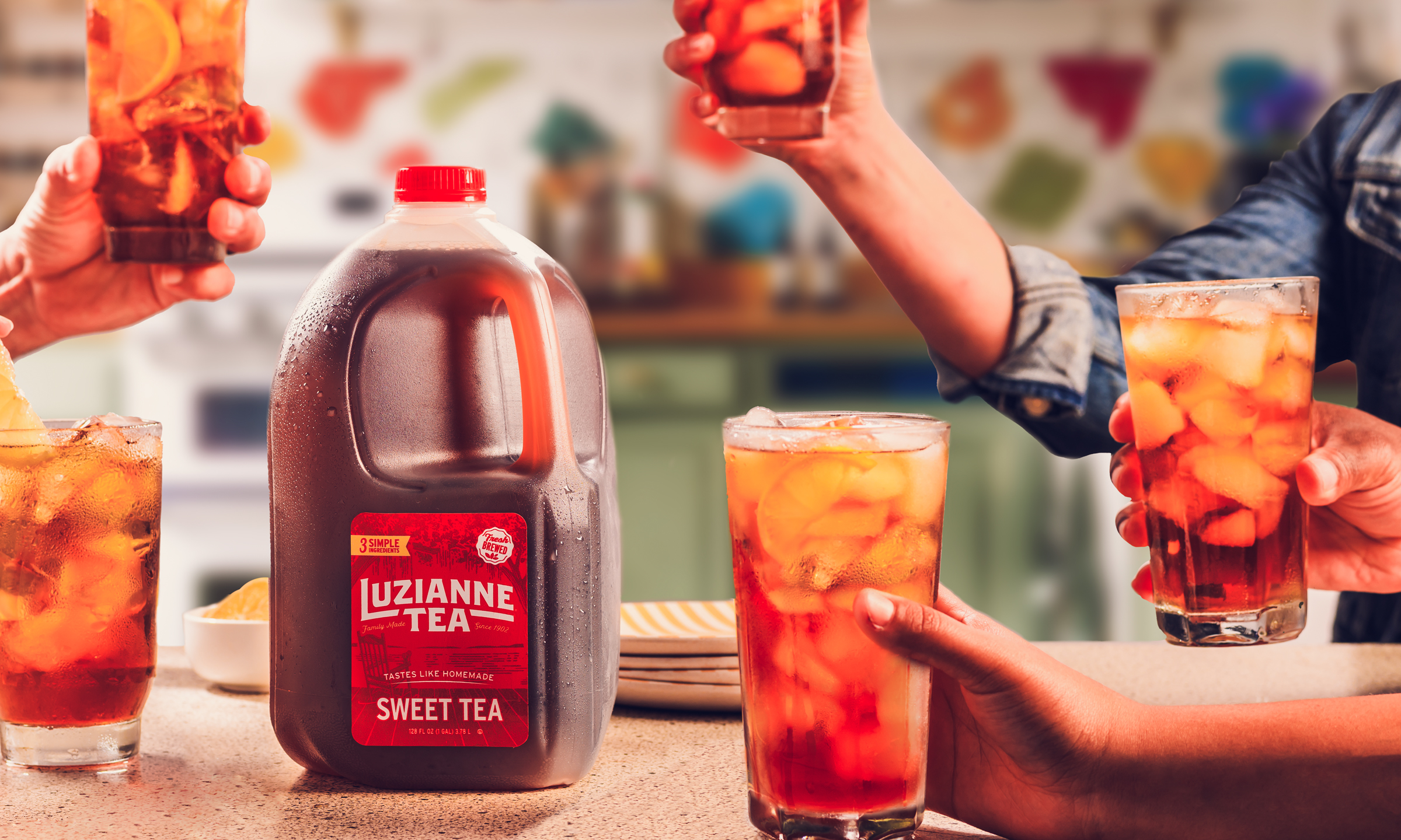 A group of people surrounding a Luzianne Tea gallon jug and cheering