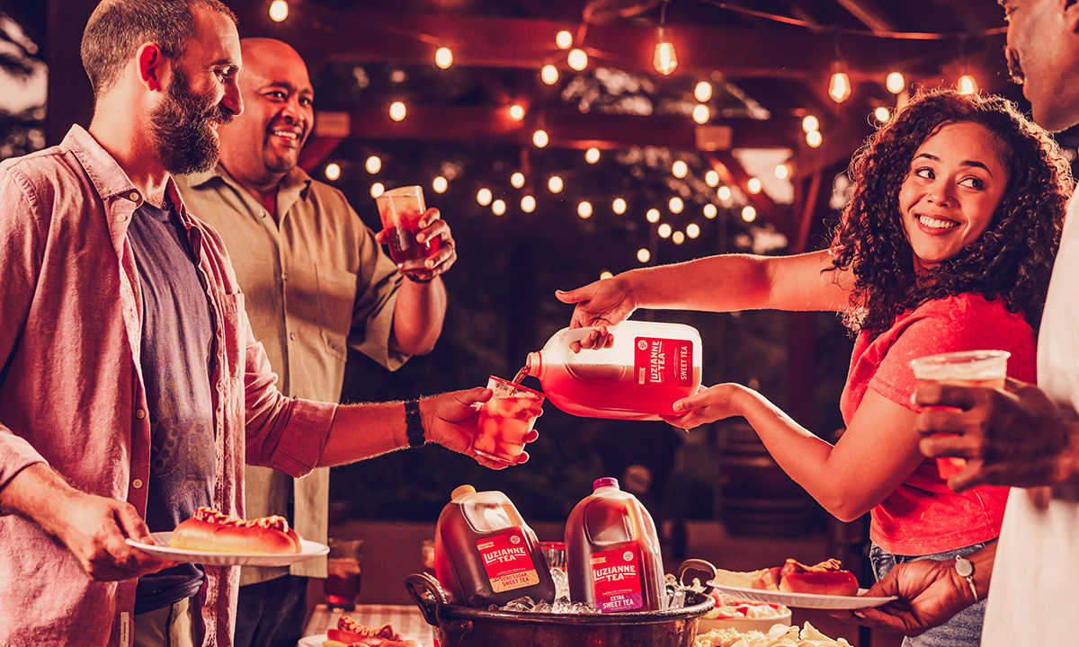 friends pouring iced tea at a nighttime BBQ